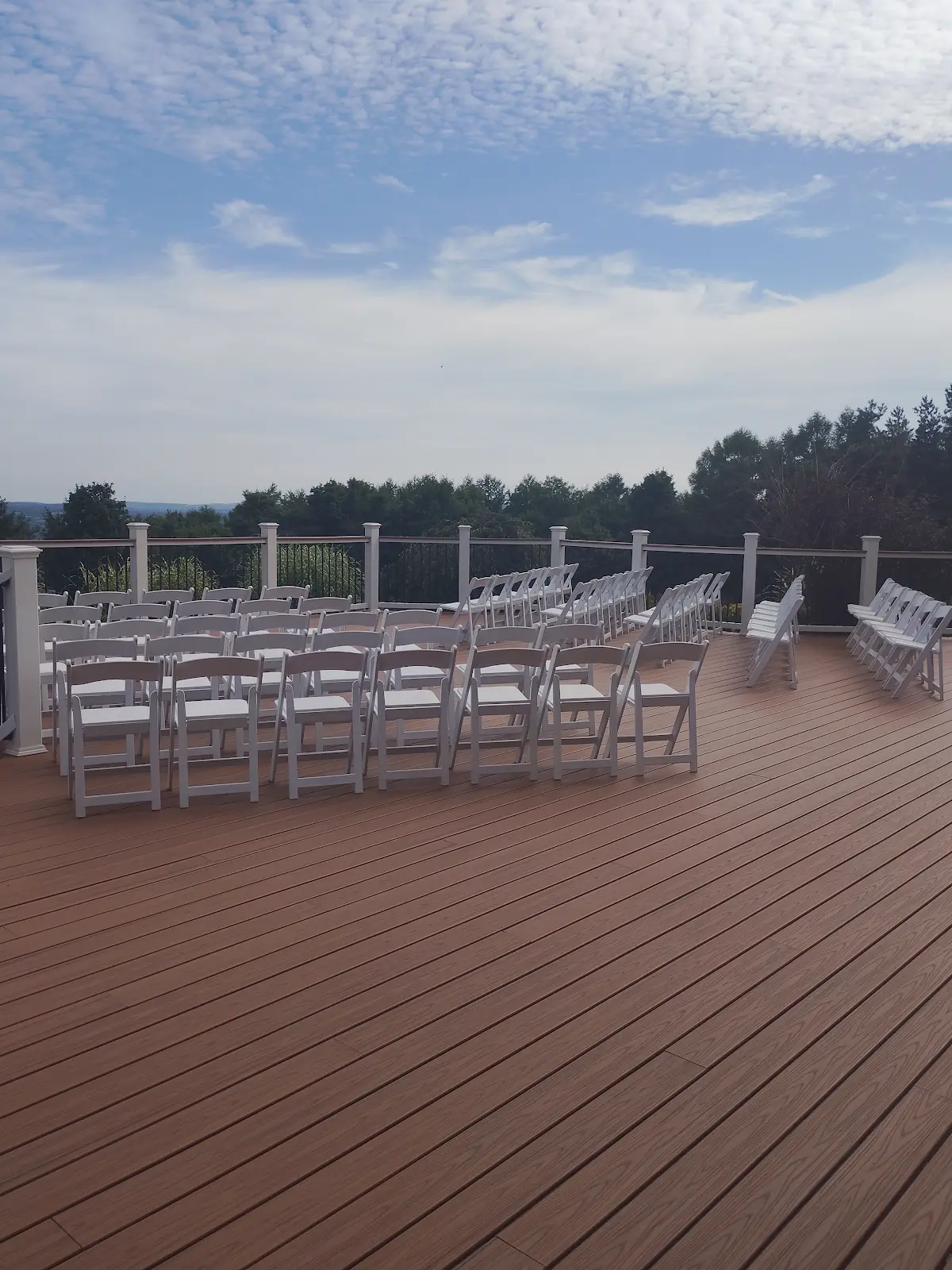 Real outdoor wedding ceremony setup with rows of white chairs on a deck